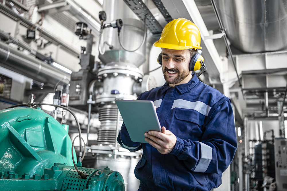 Industrial engineer standing by gas generator in power plant and